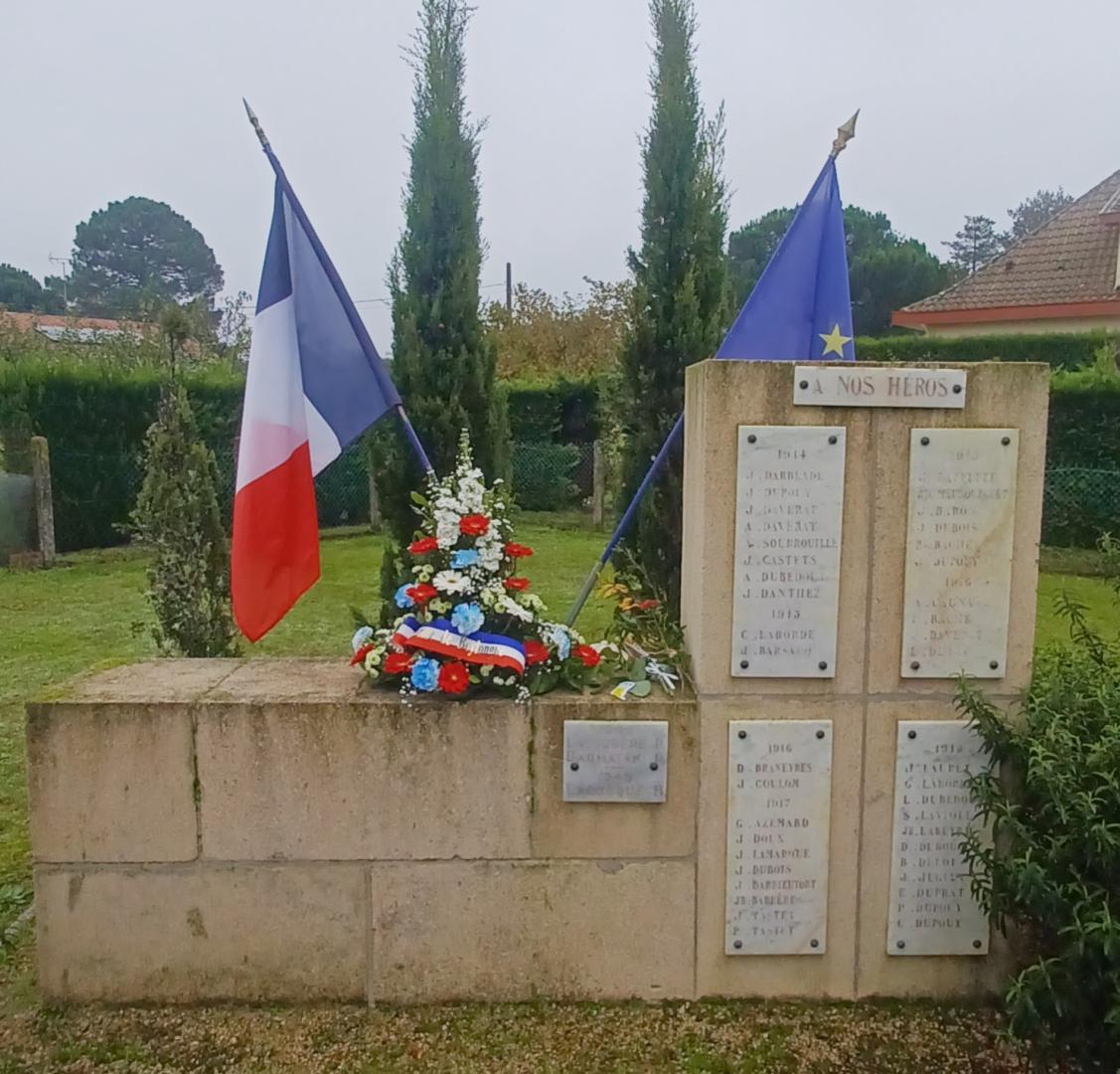 Drapeaus français et européen et gerbe de fleurs sur le monument aux morts